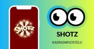 Kuvassa vasemmalla Shotz Casinon logo älypuhelimen näytöllä, ja vasemmalla Slotsoon isot pyöreät pallosilmät, jotka katsovat älypuhelimen suuntaan. Silmien alla teksti: Shotz kasinoarvostelu. Kuvan tausta on raikkaan sini-vihreä.