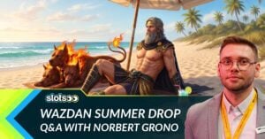 the text Wazdan Summer Drop Q&A with Norbert Grono and a photo of him in the foreground. In the background is a greek god chilling on a sand beach together with his three headed dog cerberus